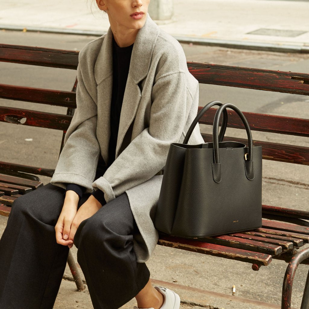Angela Roi Vegan Cher Tote in Black, with model on bench