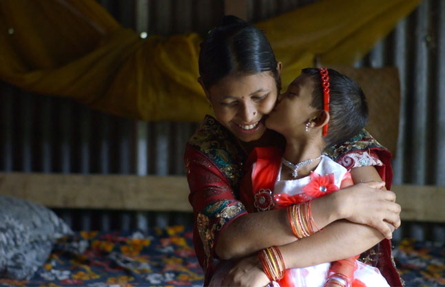 A film still from The True Cost featuring a Bangladeshi garment worker and her daughter.
